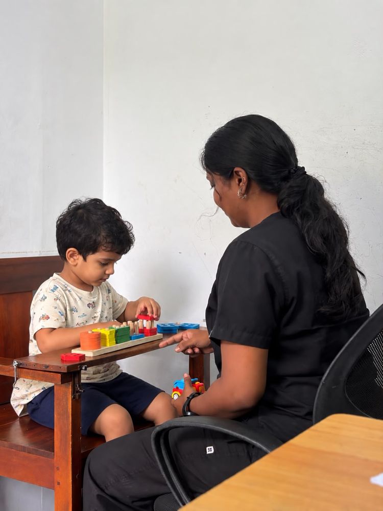 A therapist and a young child playing with wooden shape puzzles at Alora